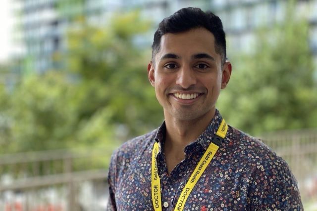 A man in a floral shirt wearing a yellow lanyard showing that he is a doctor.